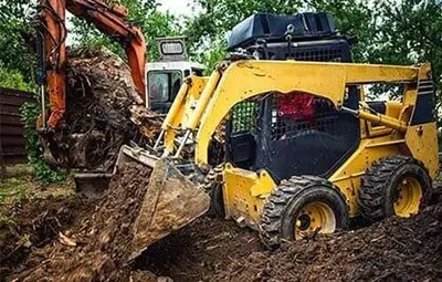 A yellow excavator is digging a hole in the middle of a forest.