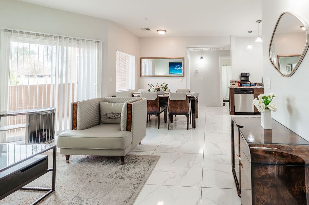 Bright, modern living and dining room with white walls, tile floors, furniture, and a long dining table.
