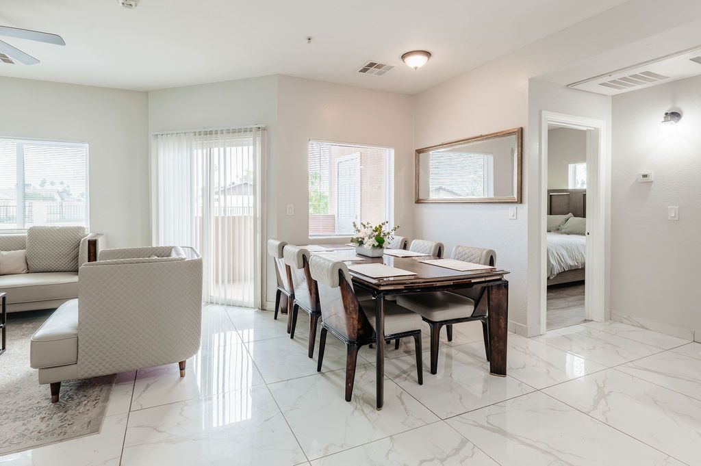 Bright, open dining and living area with table, chairs, sofa, and access to a bedroom.