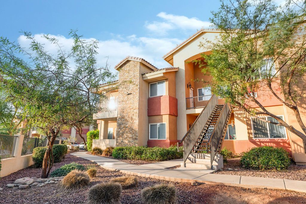 Multi-story apartment building with stucco exterior, stairs, and landscaping.