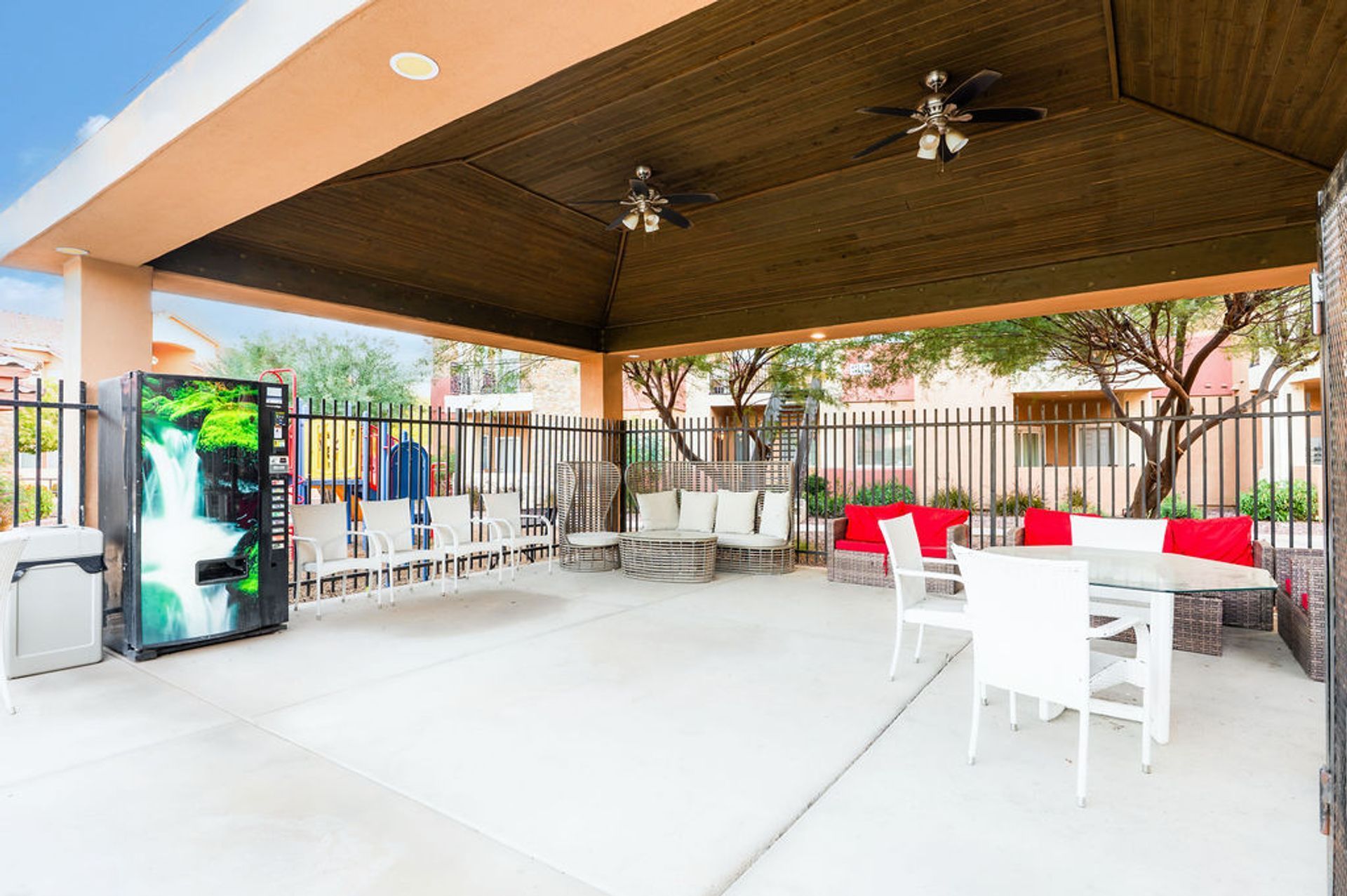 Covered outdoor patio with seating, vending machine, and ceiling fans.