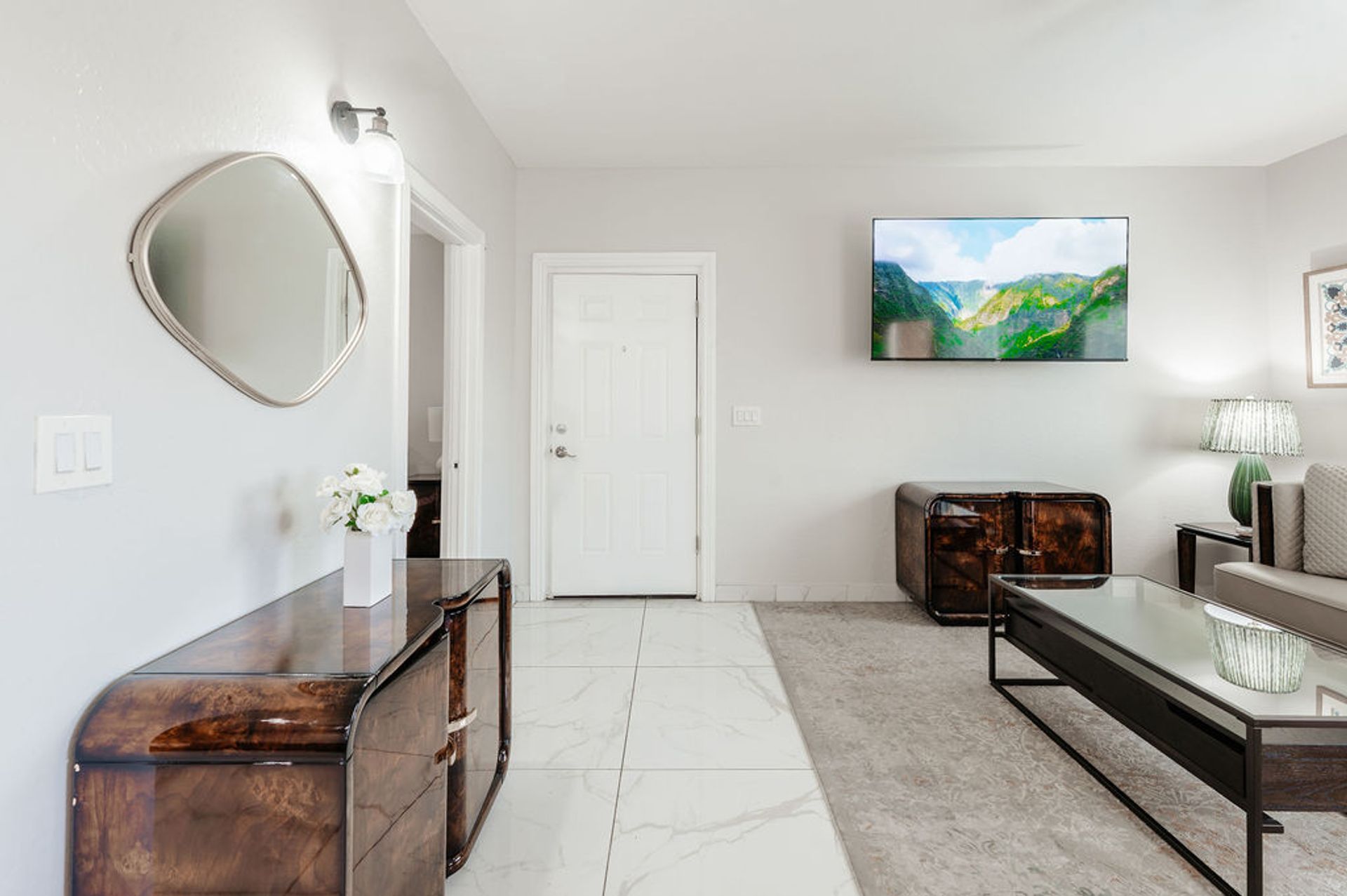 Living room with a wooden cabinet, mirror, TV, and gray rug.