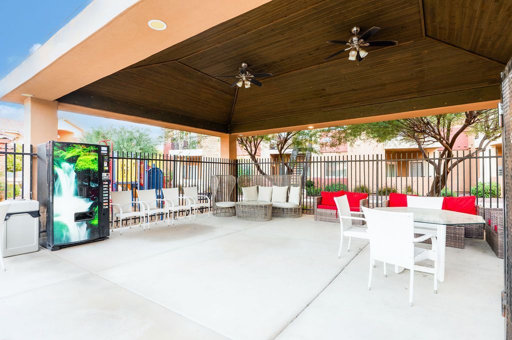 Covered outdoor seating area with tables, chairs, and vending machine.