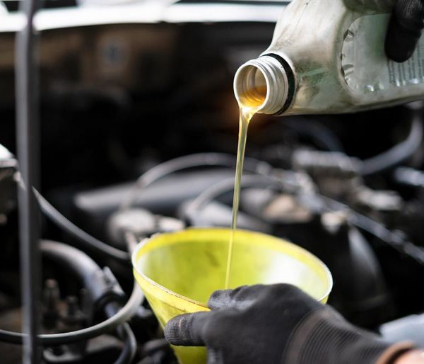 A person is pouring oil into a yellow cup