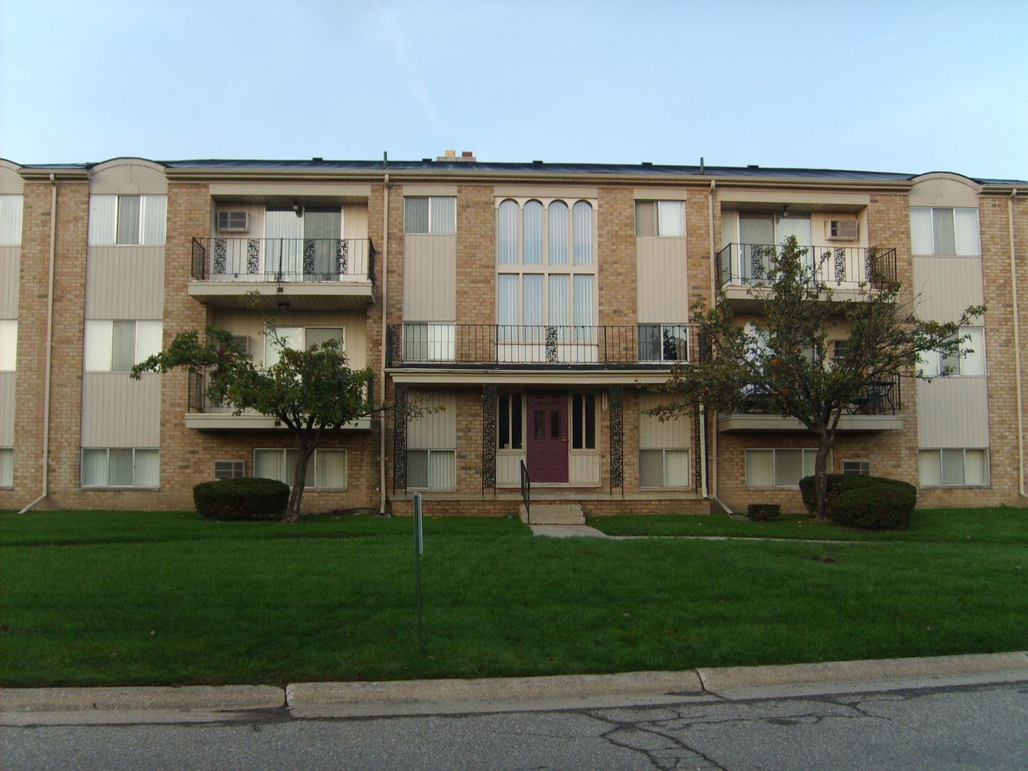 A large apartment building with a lush green lawn in front of it