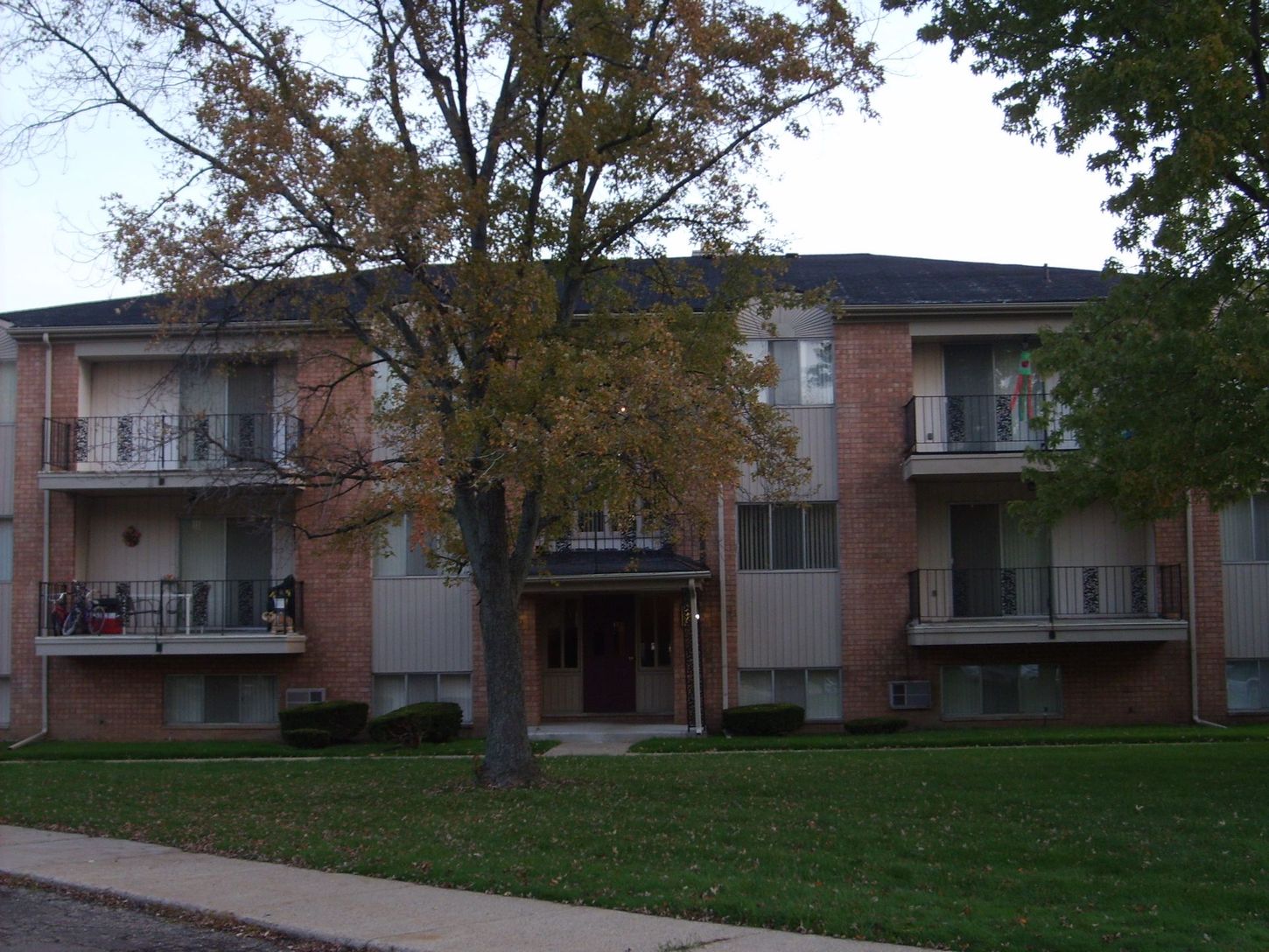 A brick apartment building with a tree in front of it