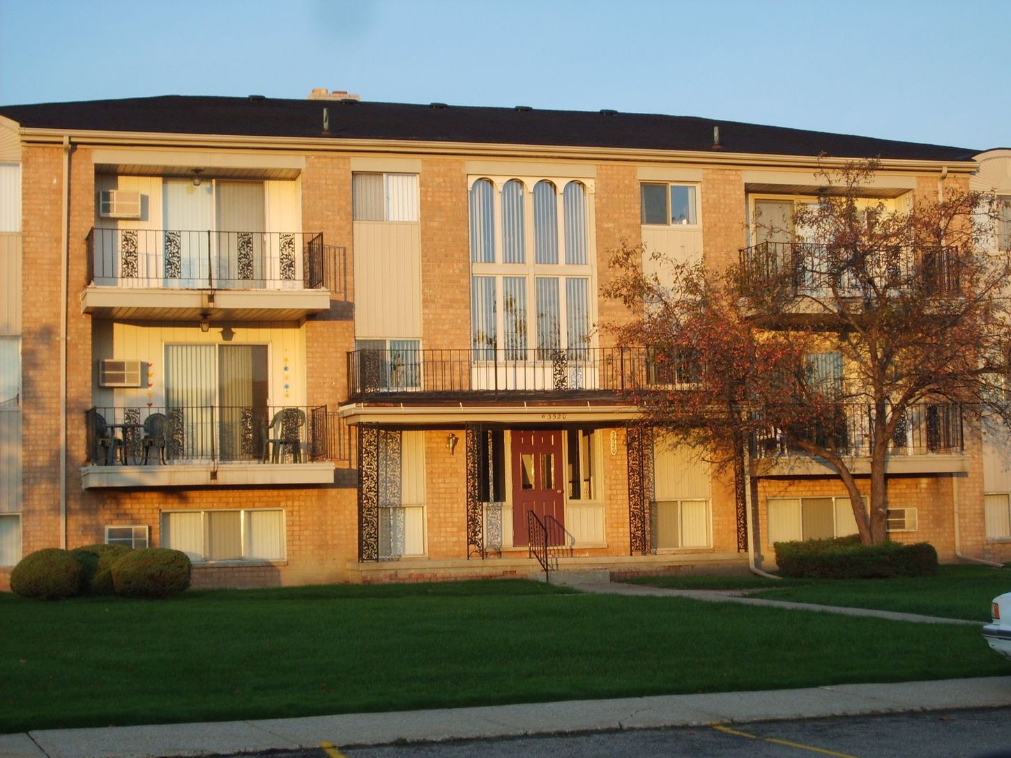 A brick apartment building with balconies and a red door