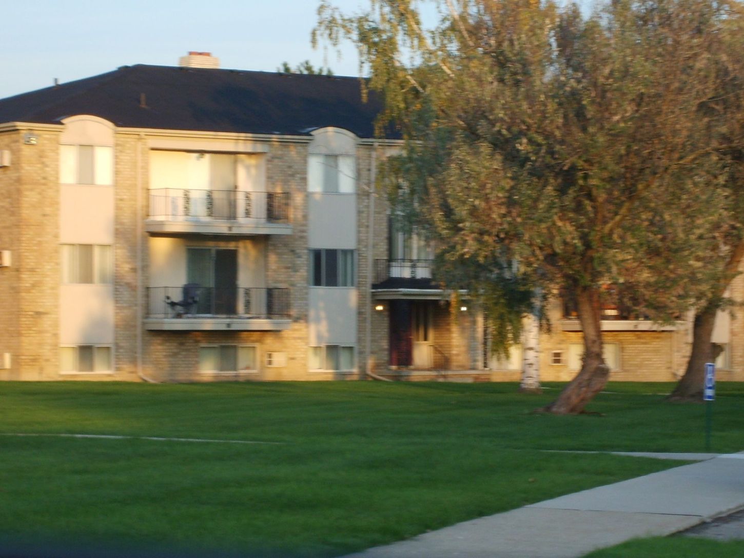 A large apartment building with a lush green lawn in front of it