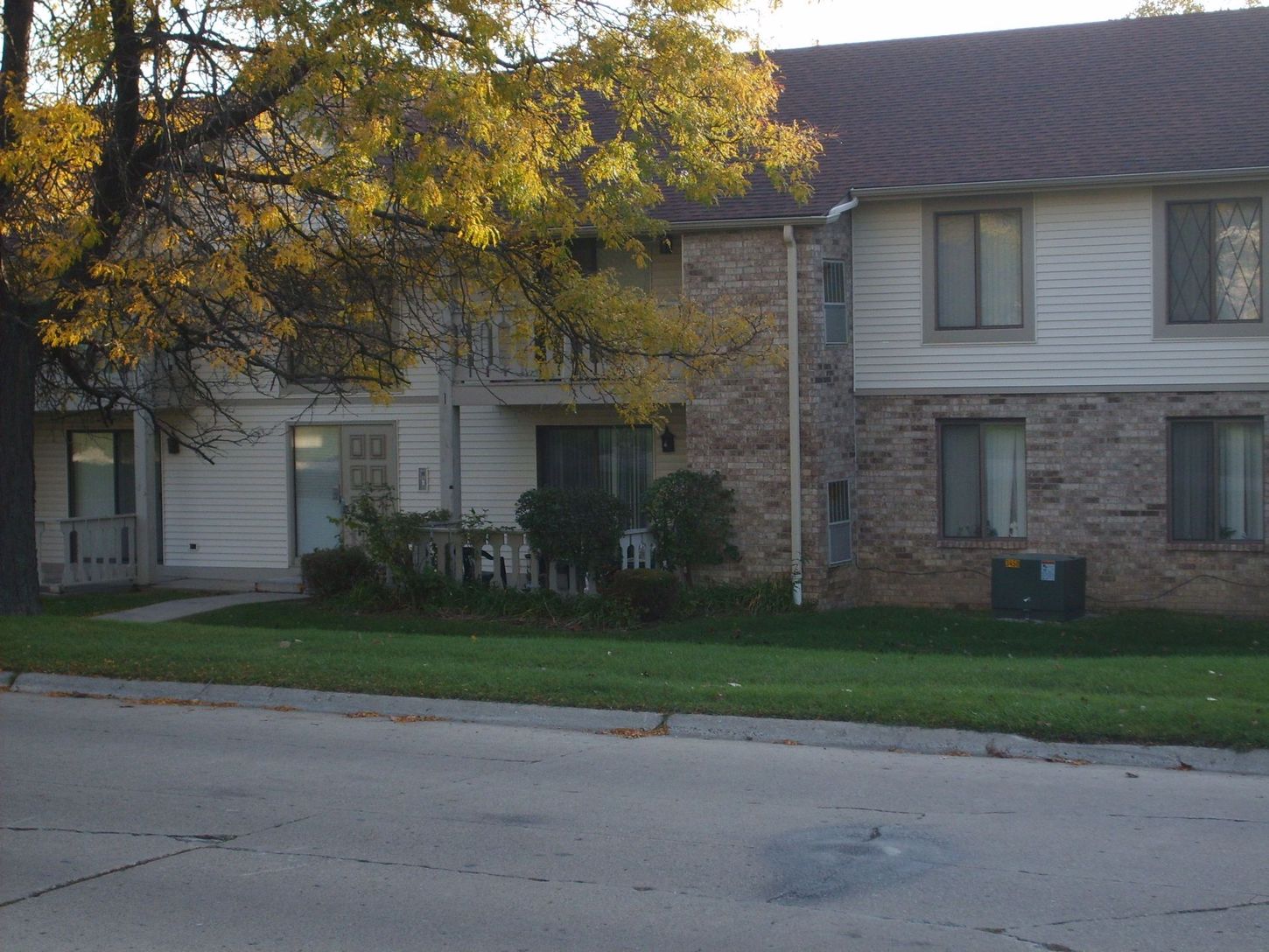 A brick and white apartment building with a tree in front of it