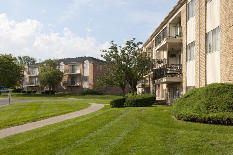 A large apartment building with a lush green lawn in front of it