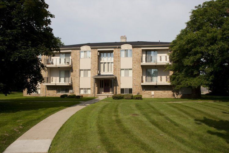 A large apartment building with a lush green lawn in front of it