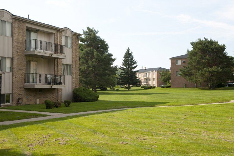 A lush green lawn in front of a brick apartment building.
