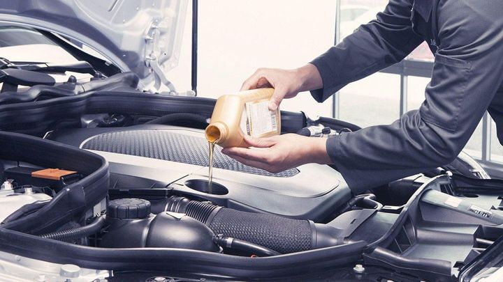 A man is pouring oil into a car engine.