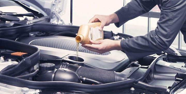 A man is pouring oil into a car engine.