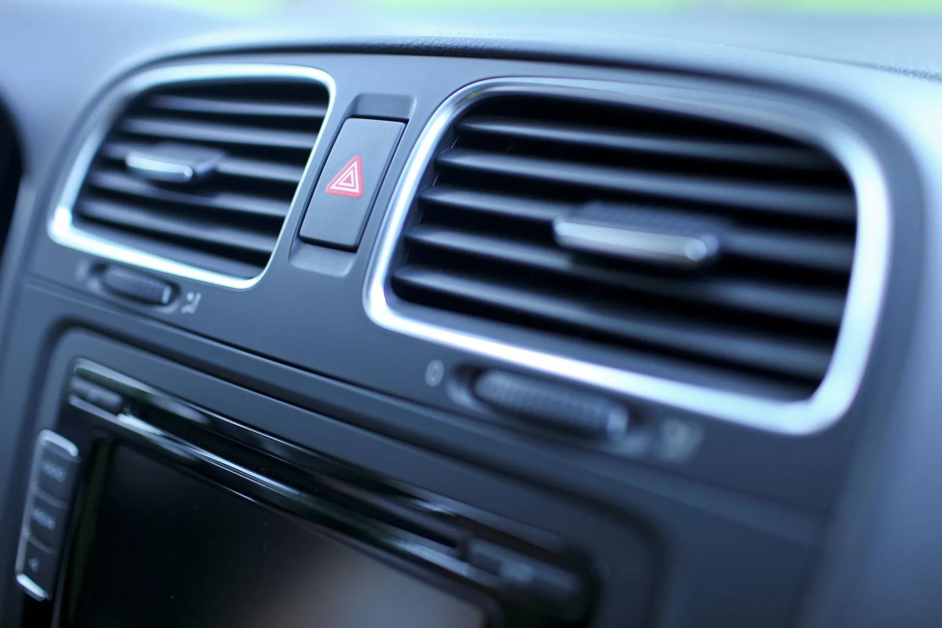 A close up of the air vents in a car with a radio.