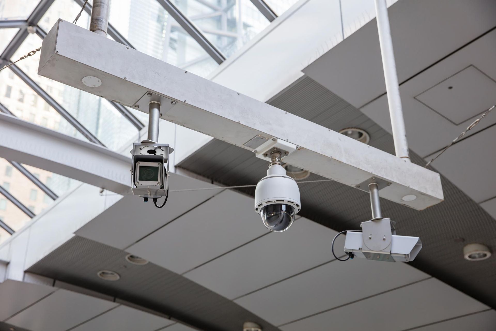 two security cameras are hanging from the ceiling of a building .