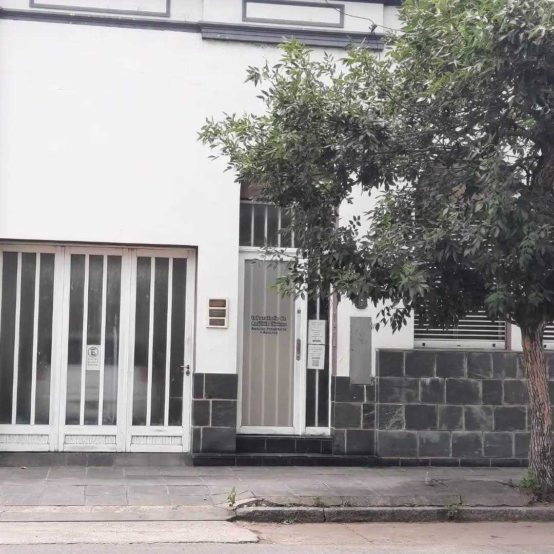Exterior de un edificio residencial blanco con una puerta de garaje de rayas verticales, una puerta de cristal