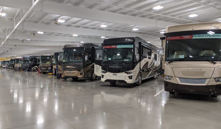 A row of rvs are parked in a large warehouse.