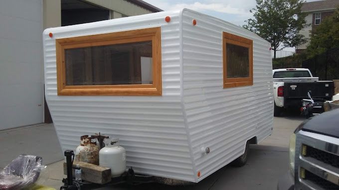 A small trailer is parked in a driveway next to a truck.