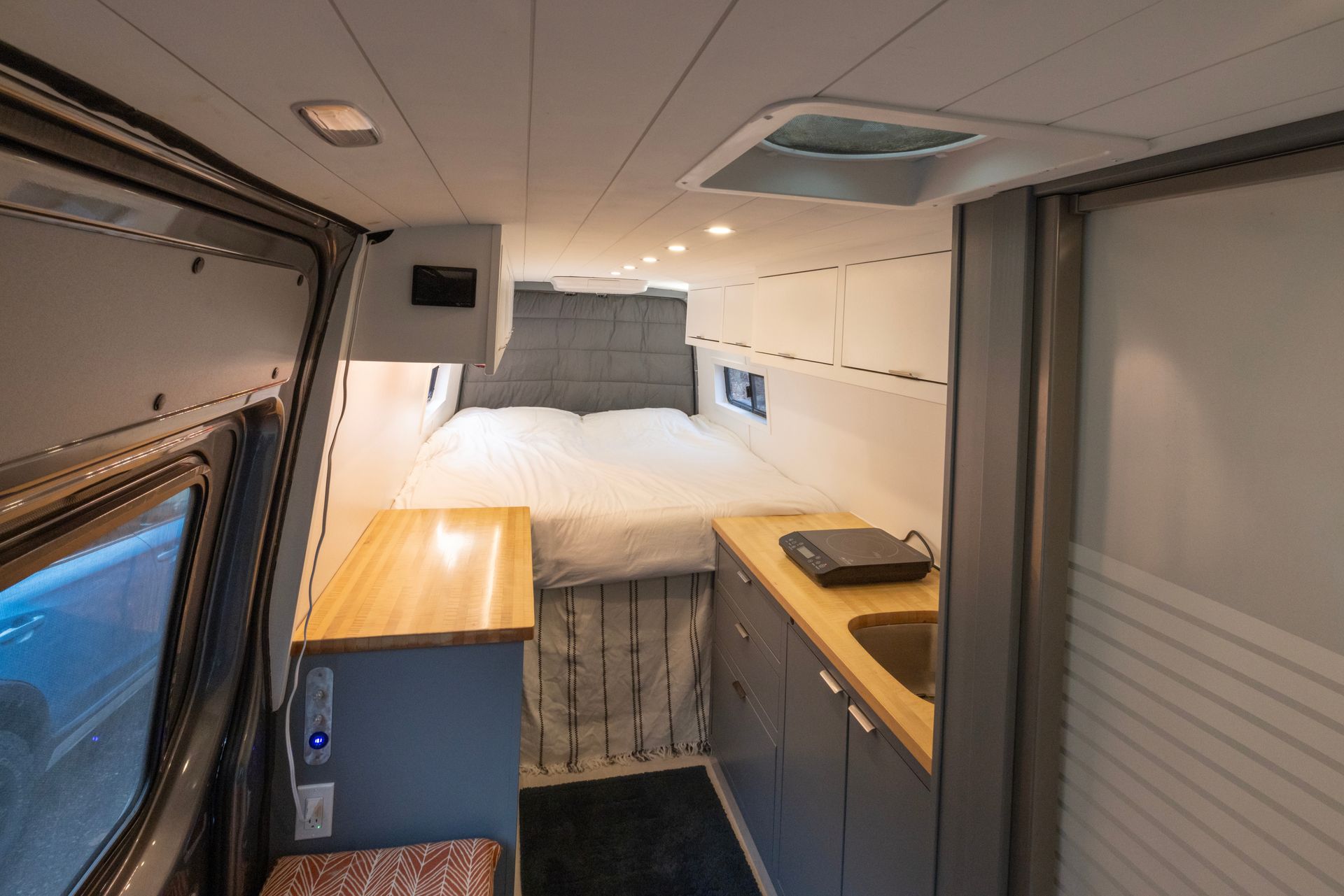 The inside of a van with a bed and a kitchen.