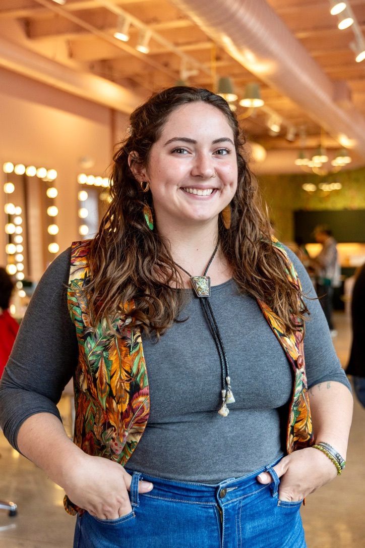 Hand holding a pink nail polish brush, a drop of polish falling, next to the bottle.