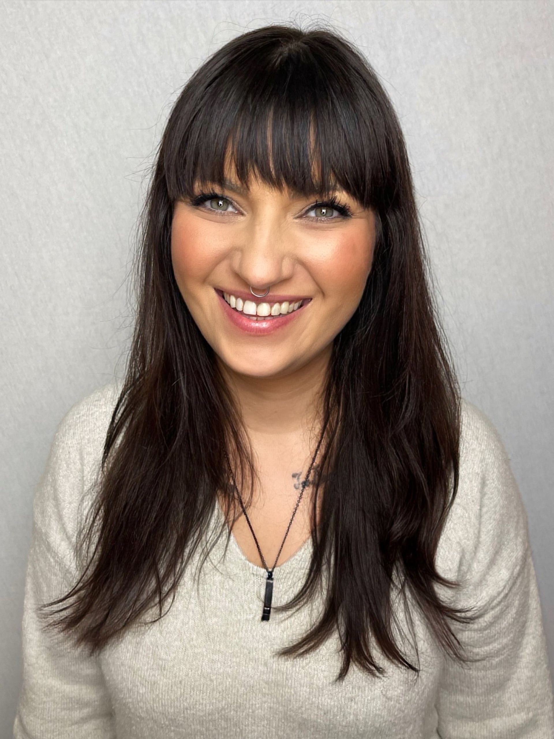 A woman with long hair and bangs is smiling for the camera.