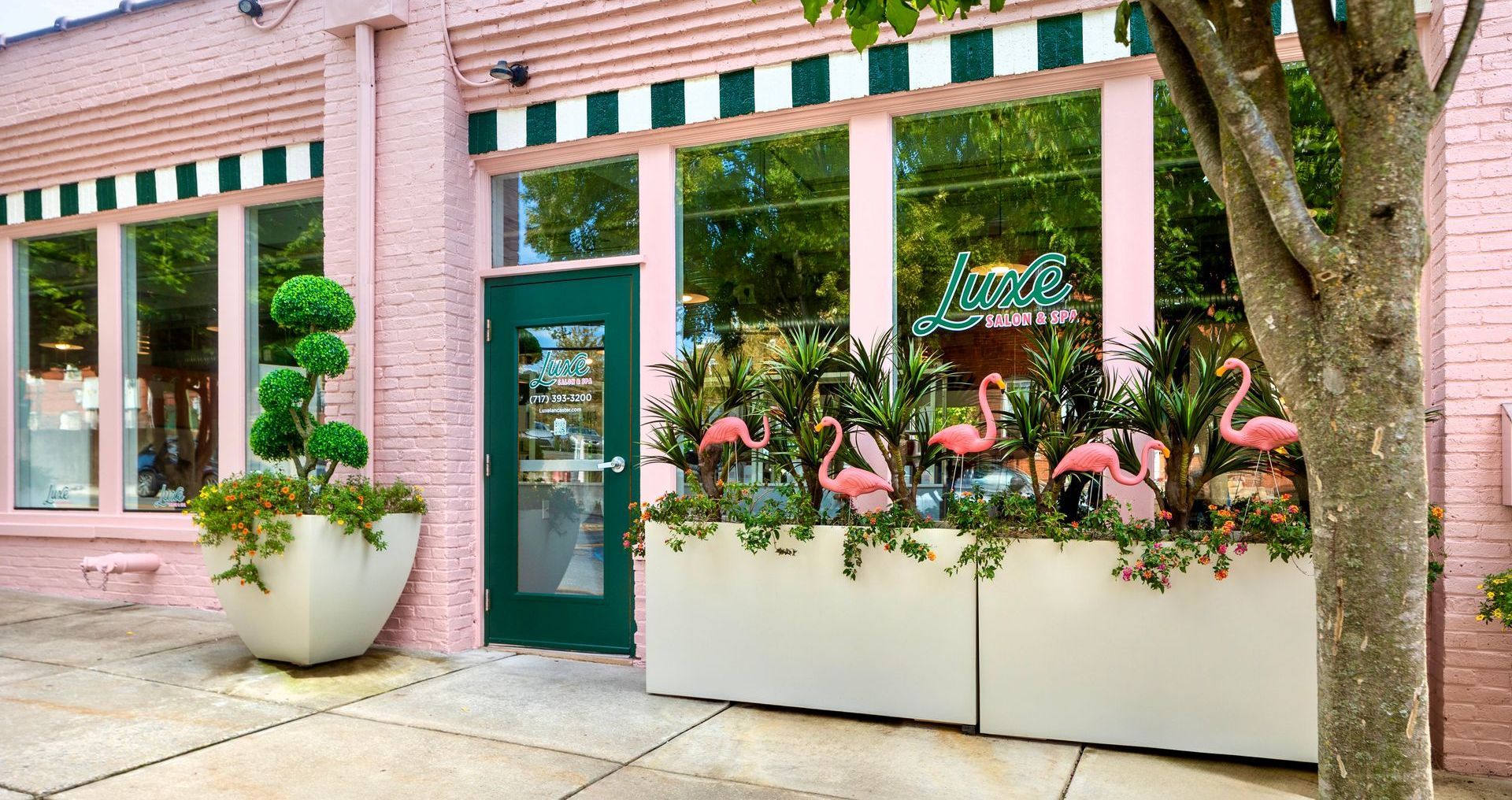 A pink brick building with flamingos in planters in front of it.