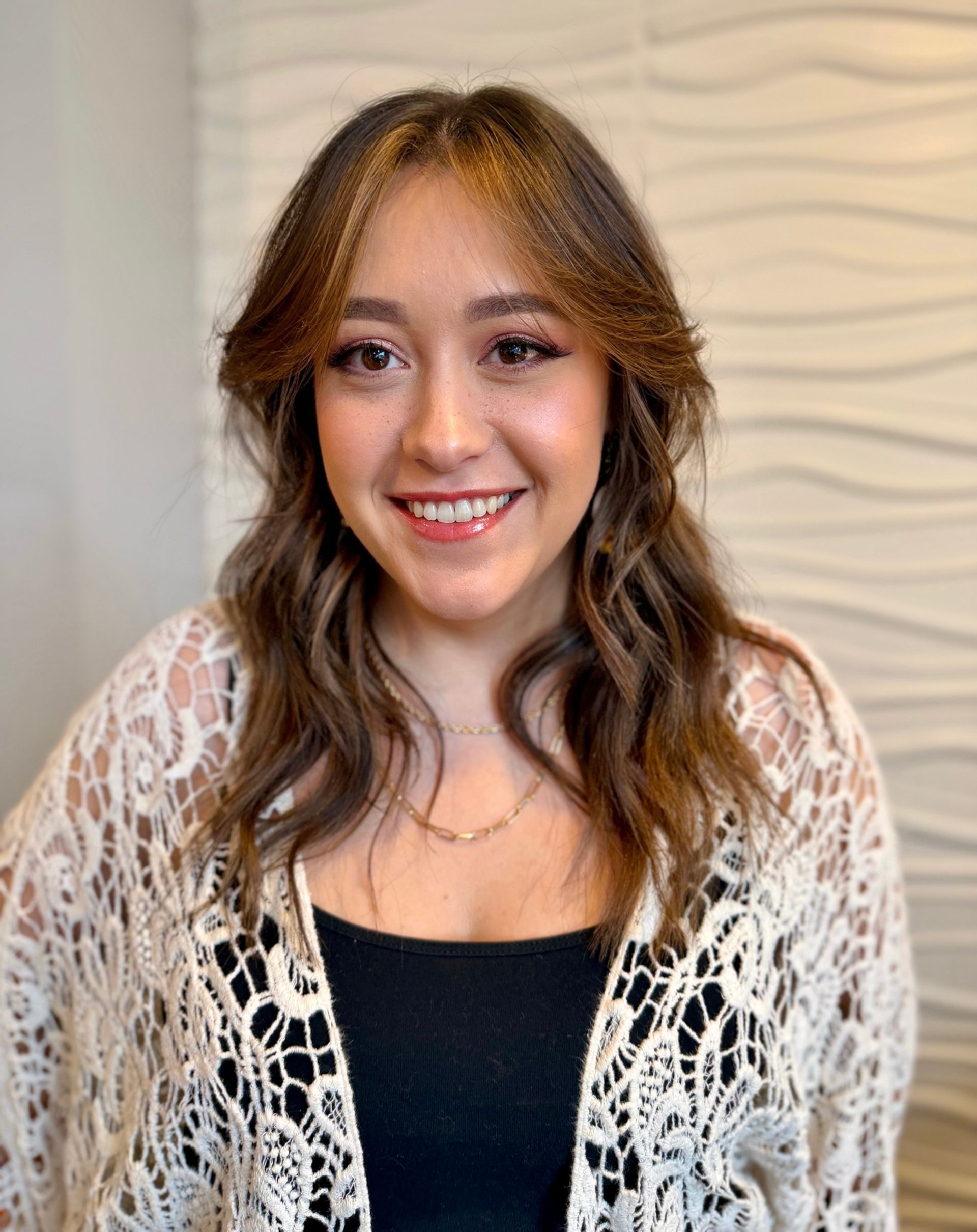 A woman wearing a white shirt and blue shorts is standing in front of a white wall.