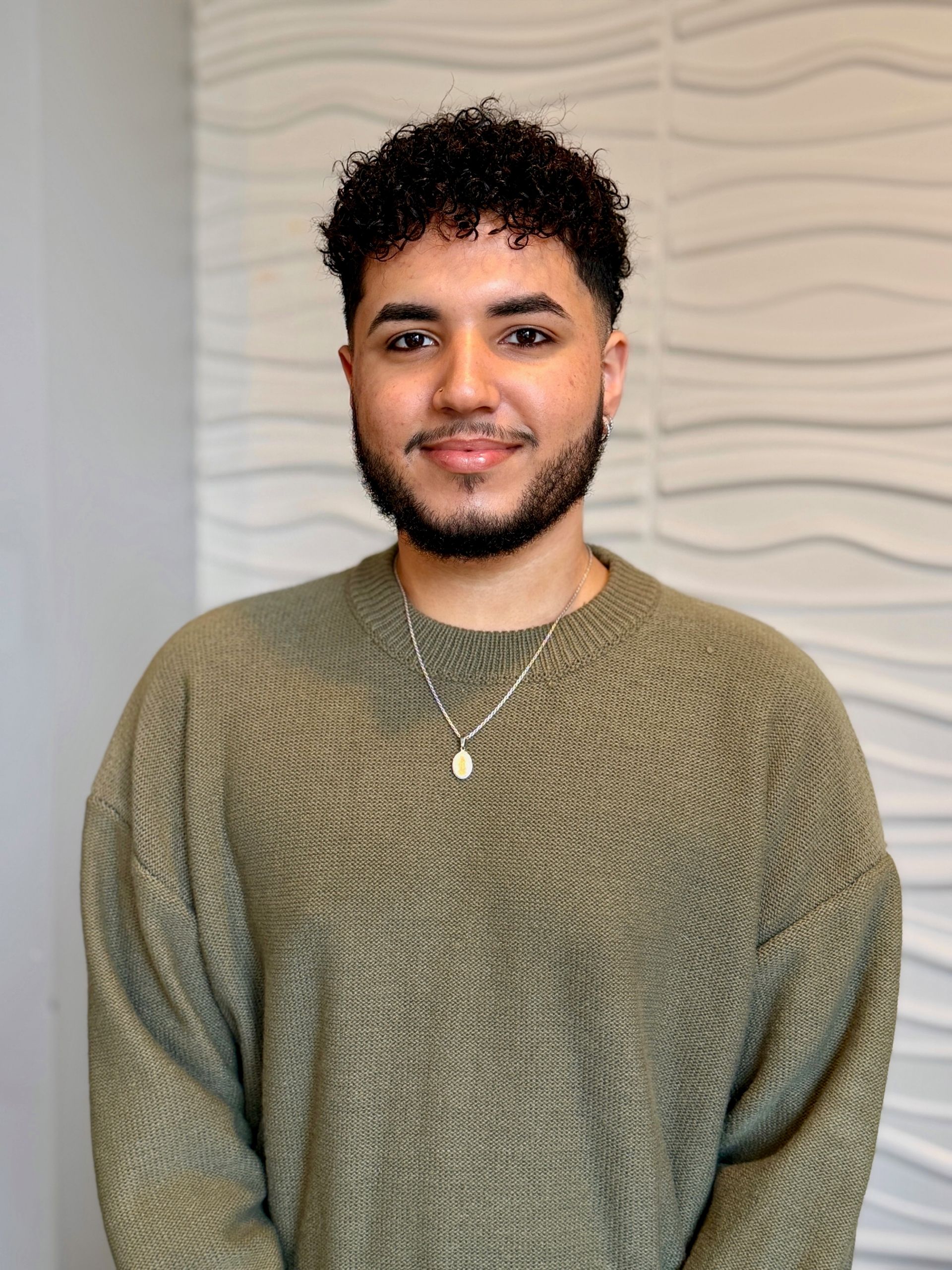 A man with curly hair is wearing a blue shirt with white flowers on it.