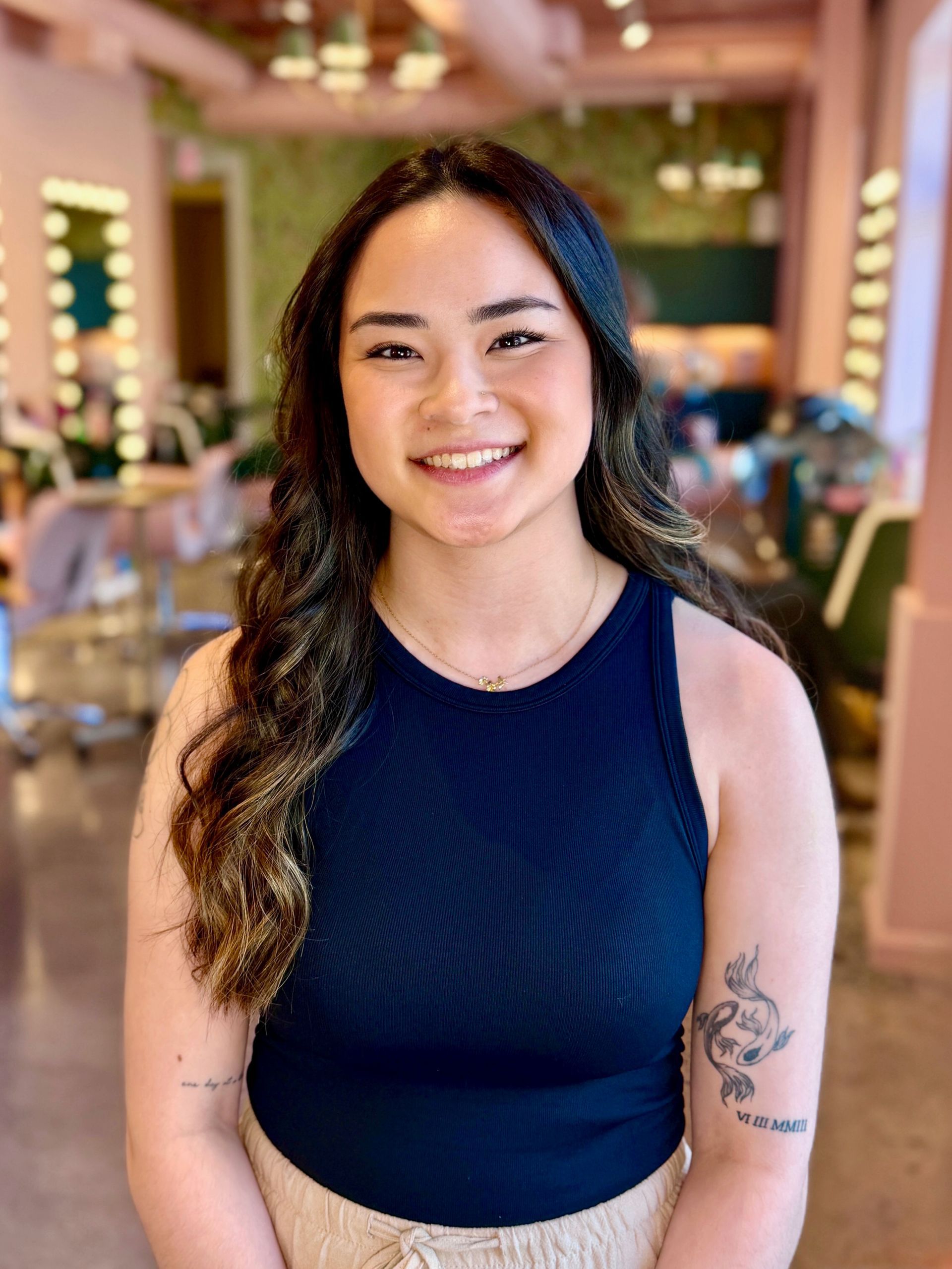 A person holds a fan of colorful nail polish swatches next to a UV nail lamp on a white table.