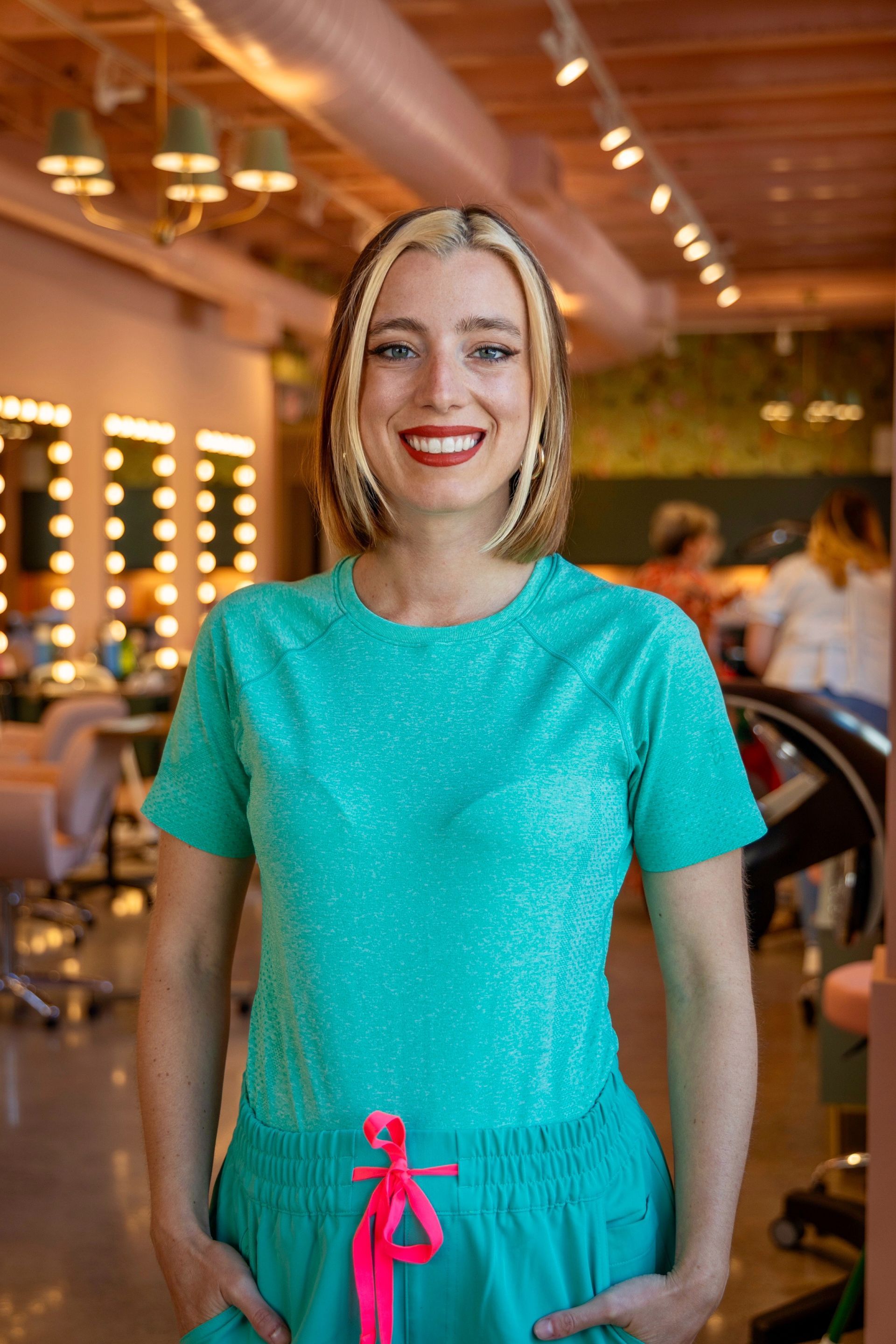 A woman is wearing a floral jumpsuit and smiling.