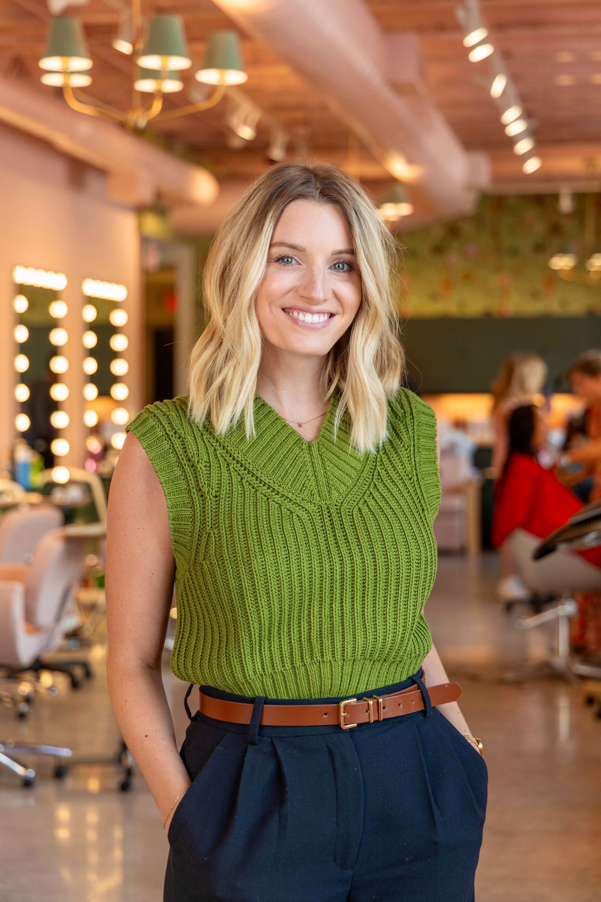 A woman wearing a black jacket and a striped top smiles for the camera