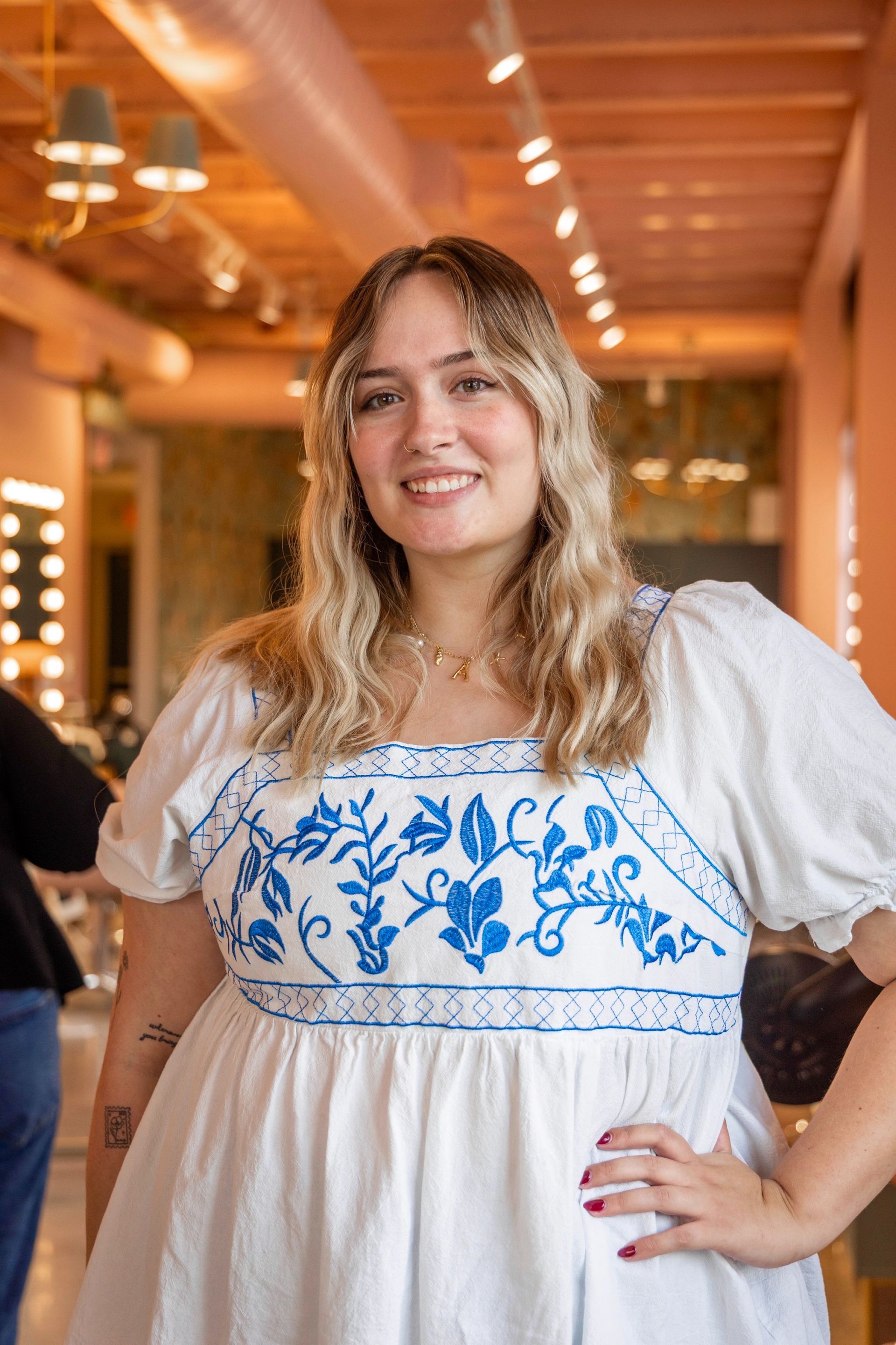 A woman is wearing a white top with ruffled sleeves and smiling.
