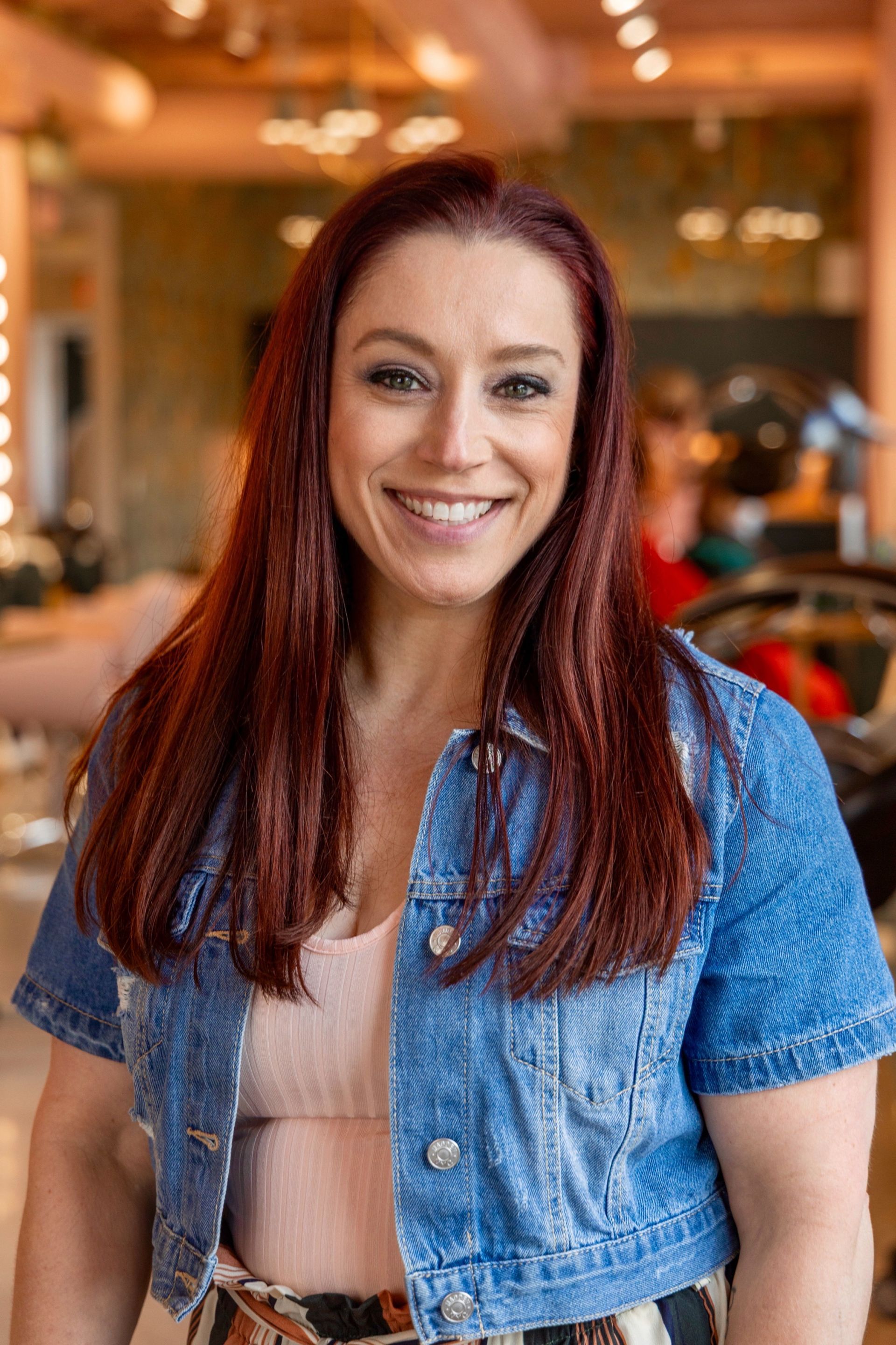 A woman wearing a black sweater and a necklace is smiling for the camera.