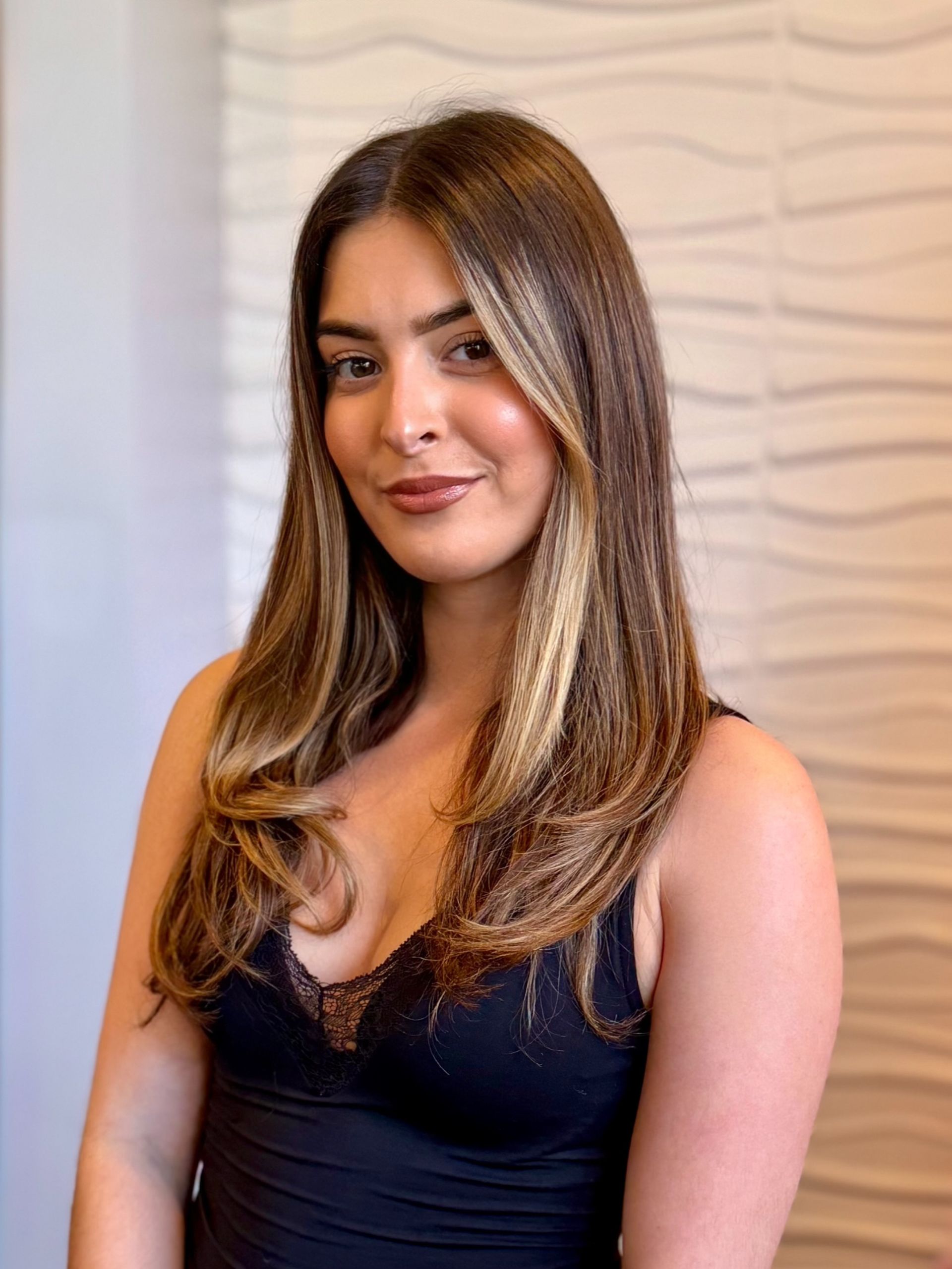 A woman is wearing a white off the shoulder top and black pants.