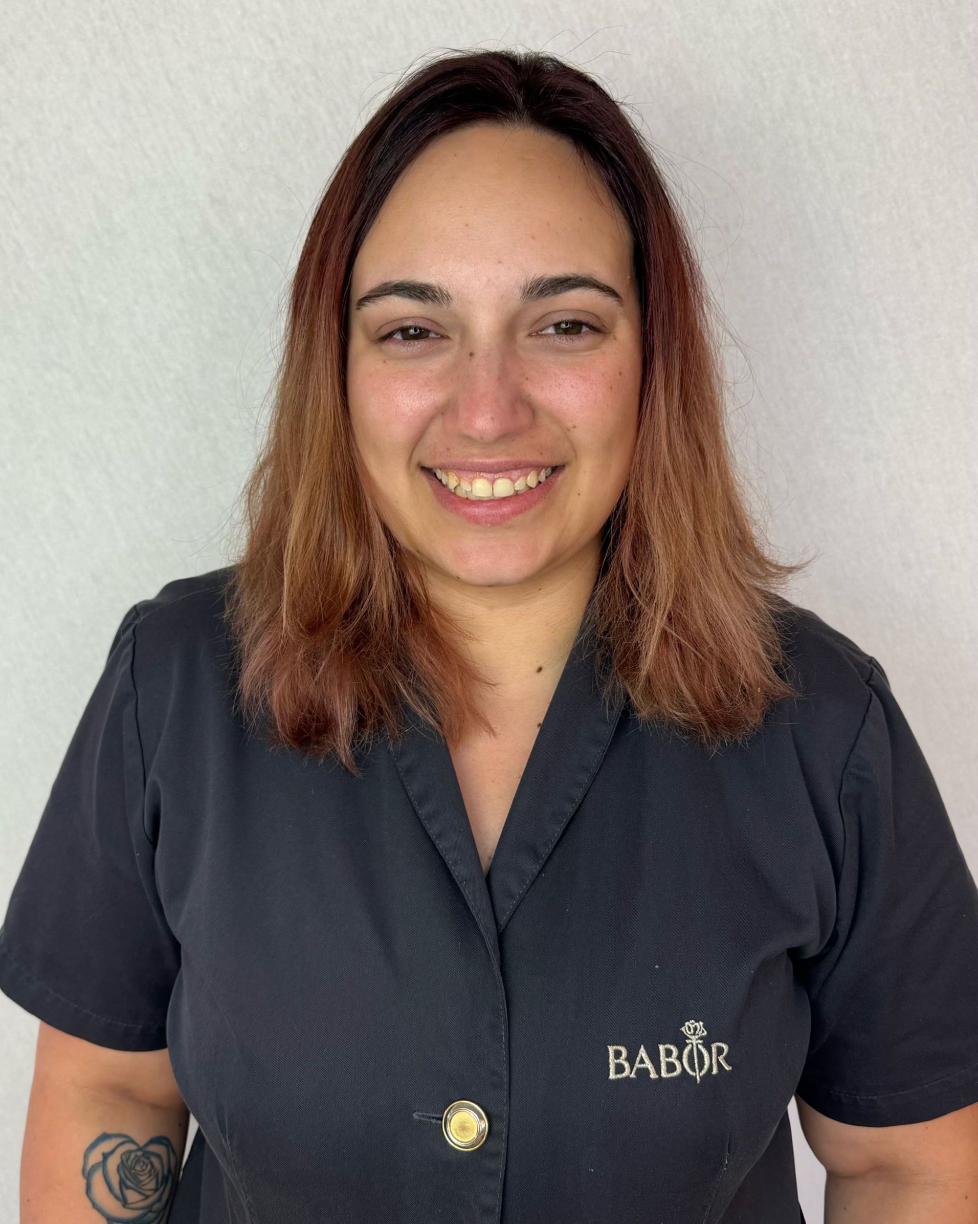 A woman wearing a black babor shirt is smiling for the camera.