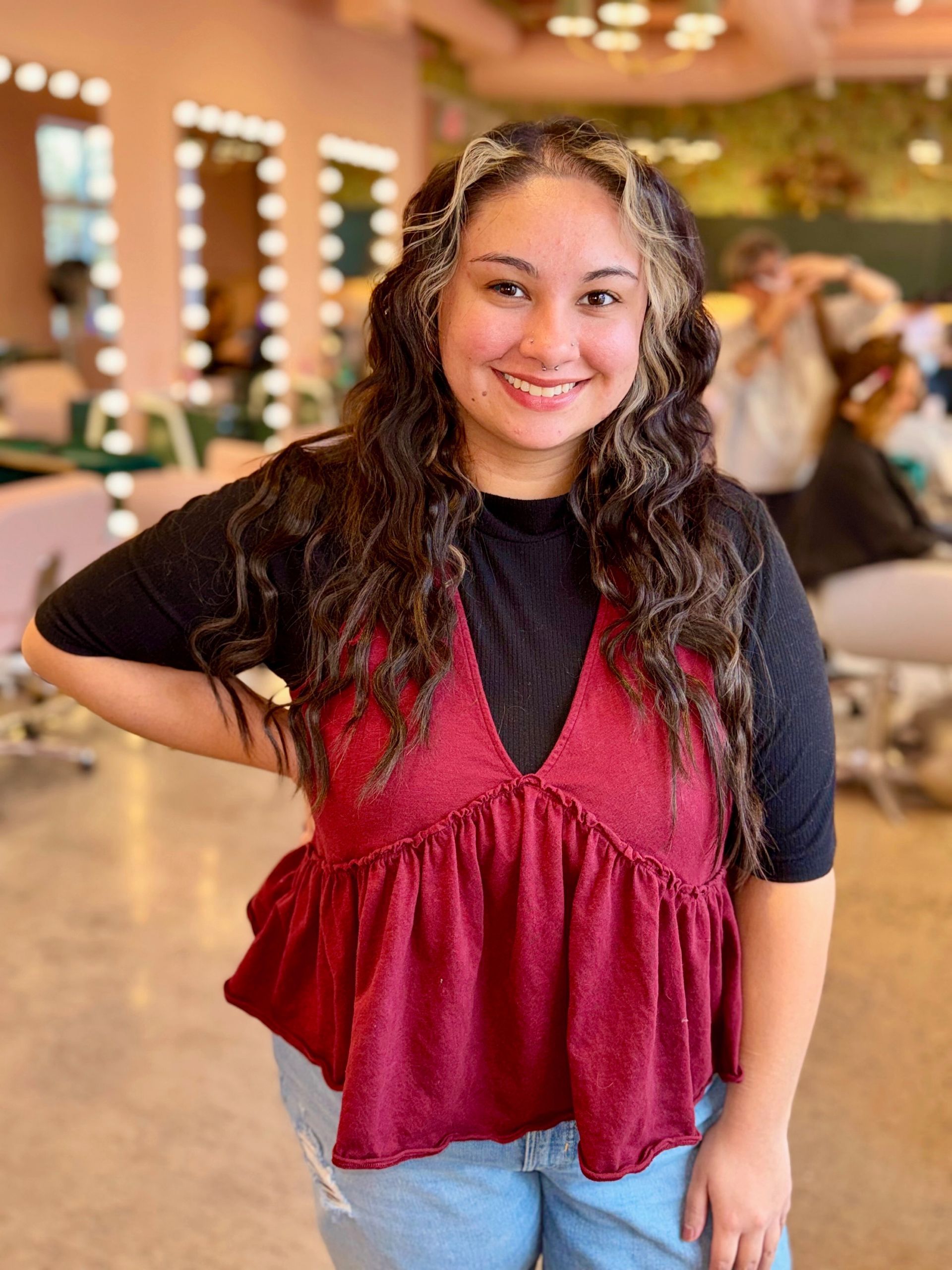 A woman in a black shirt is smiling and holding her hair