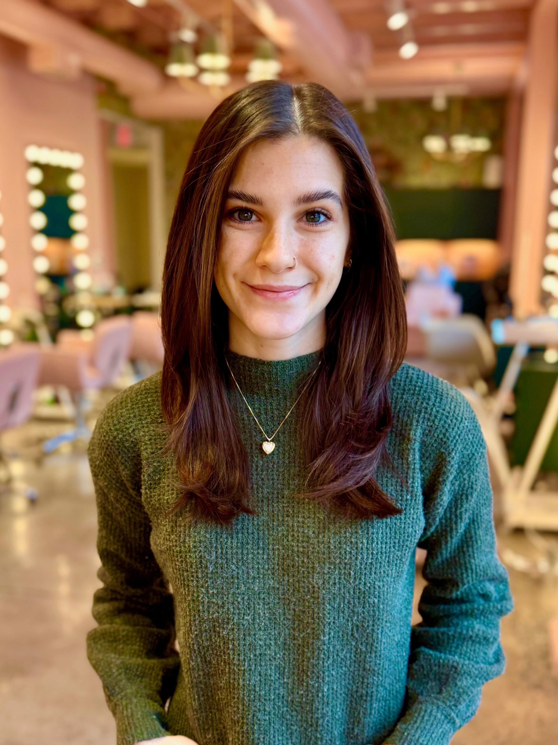 A woman in a blue dress is smiling and standing with her hands in her pockets.