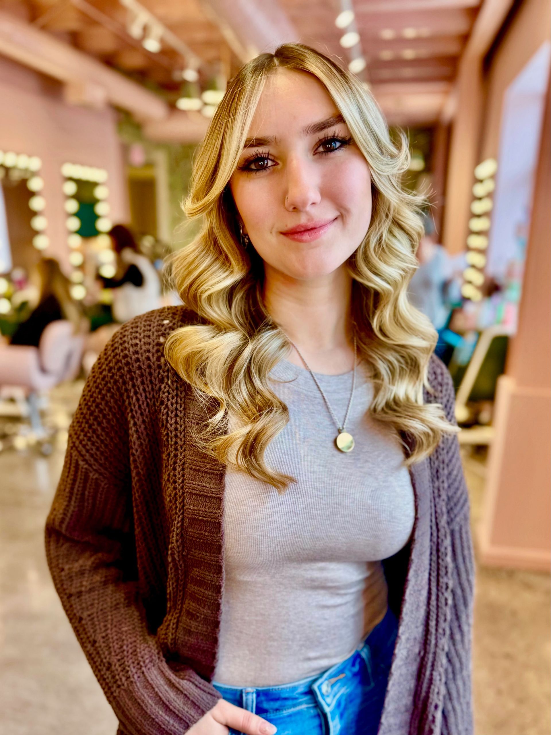 A woman in a floral dress and cardigan is smiling for the camera.