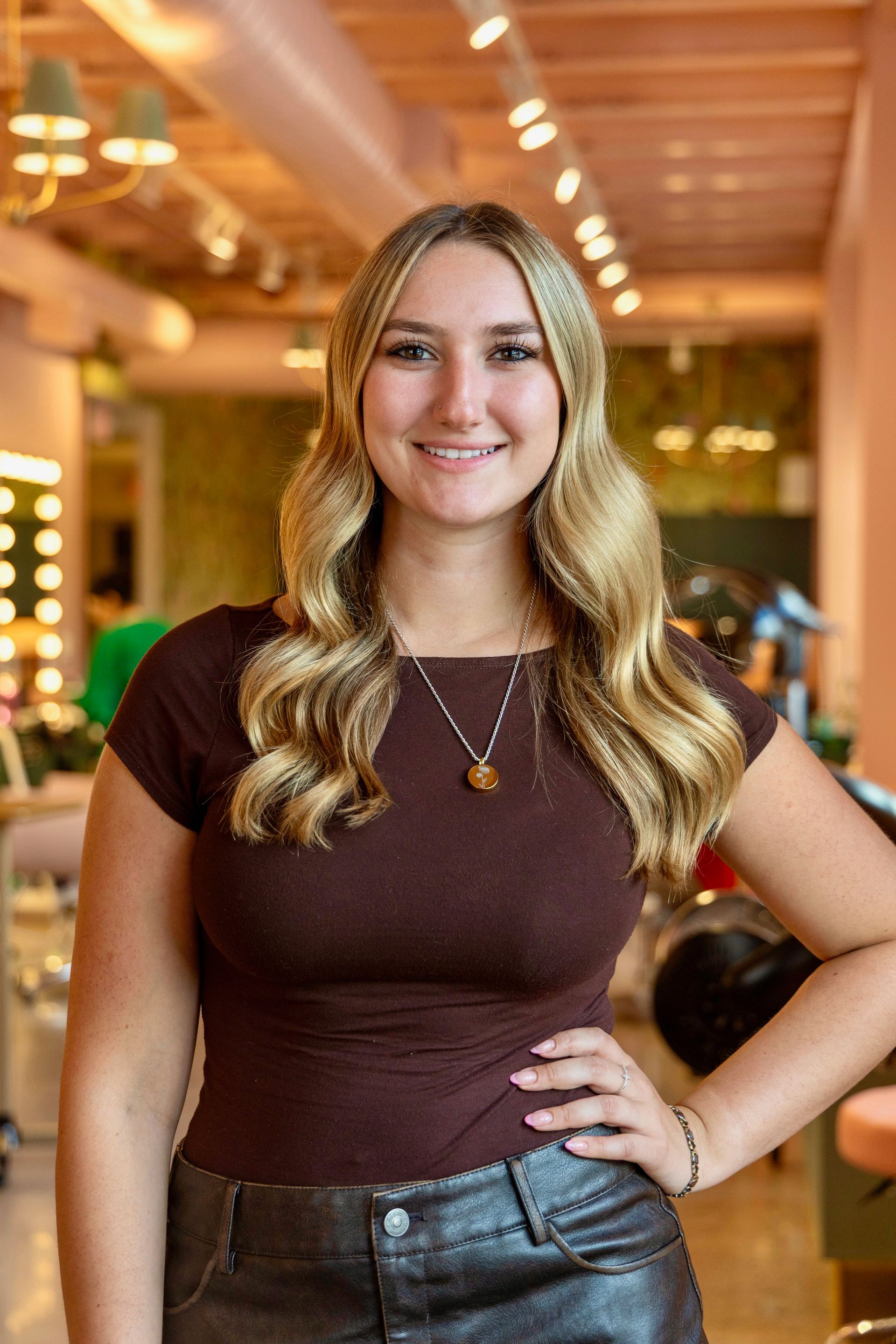 A woman in a floral dress and cardigan is smiling for the camera.