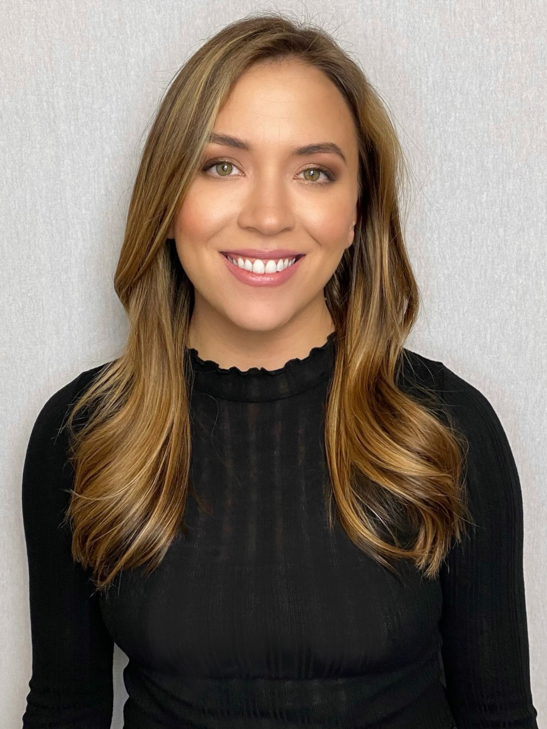 The woman is wearing a black sweater and smiling for the camera.