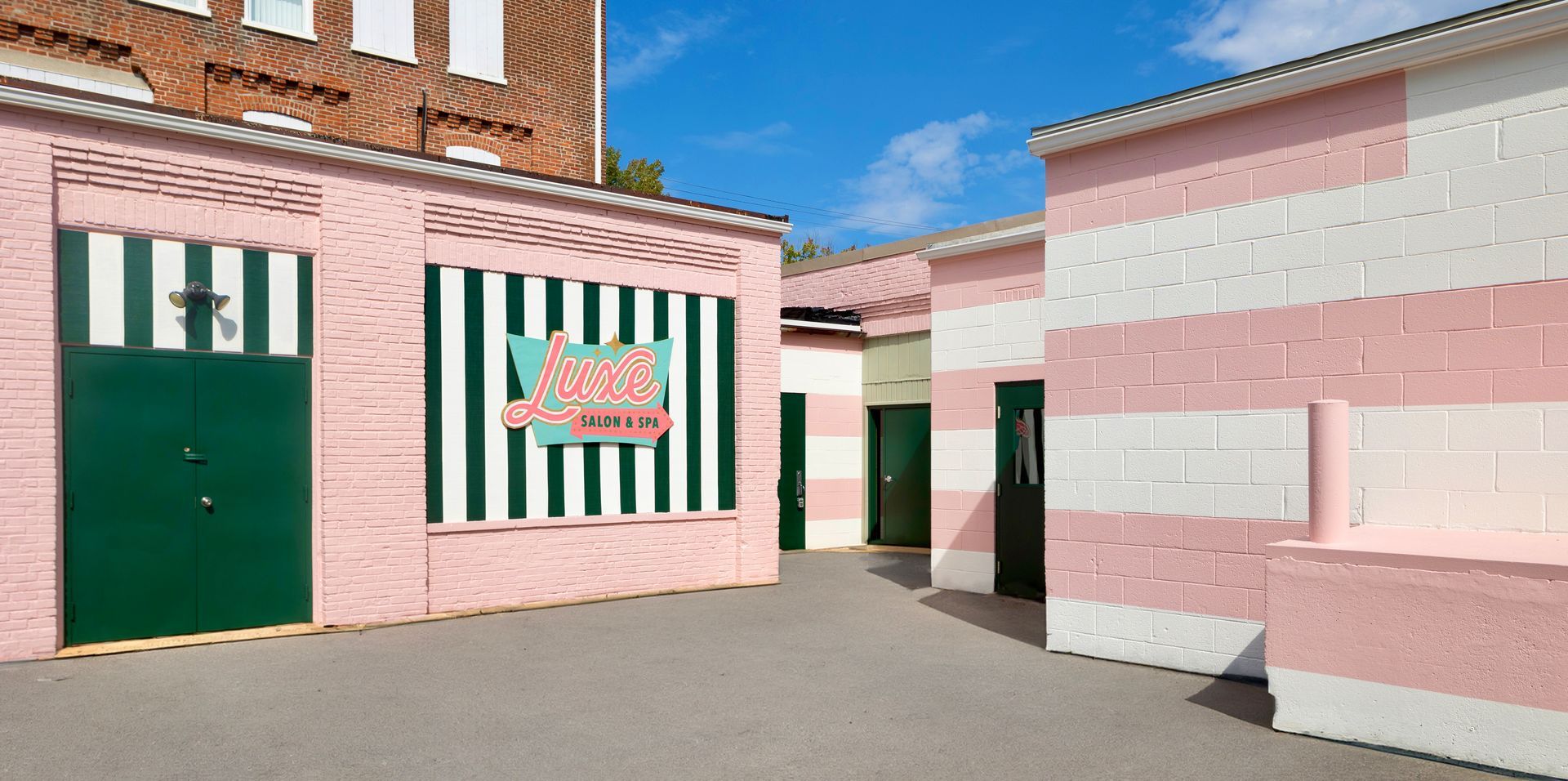 A pink and white striped building with green doors and windows. 