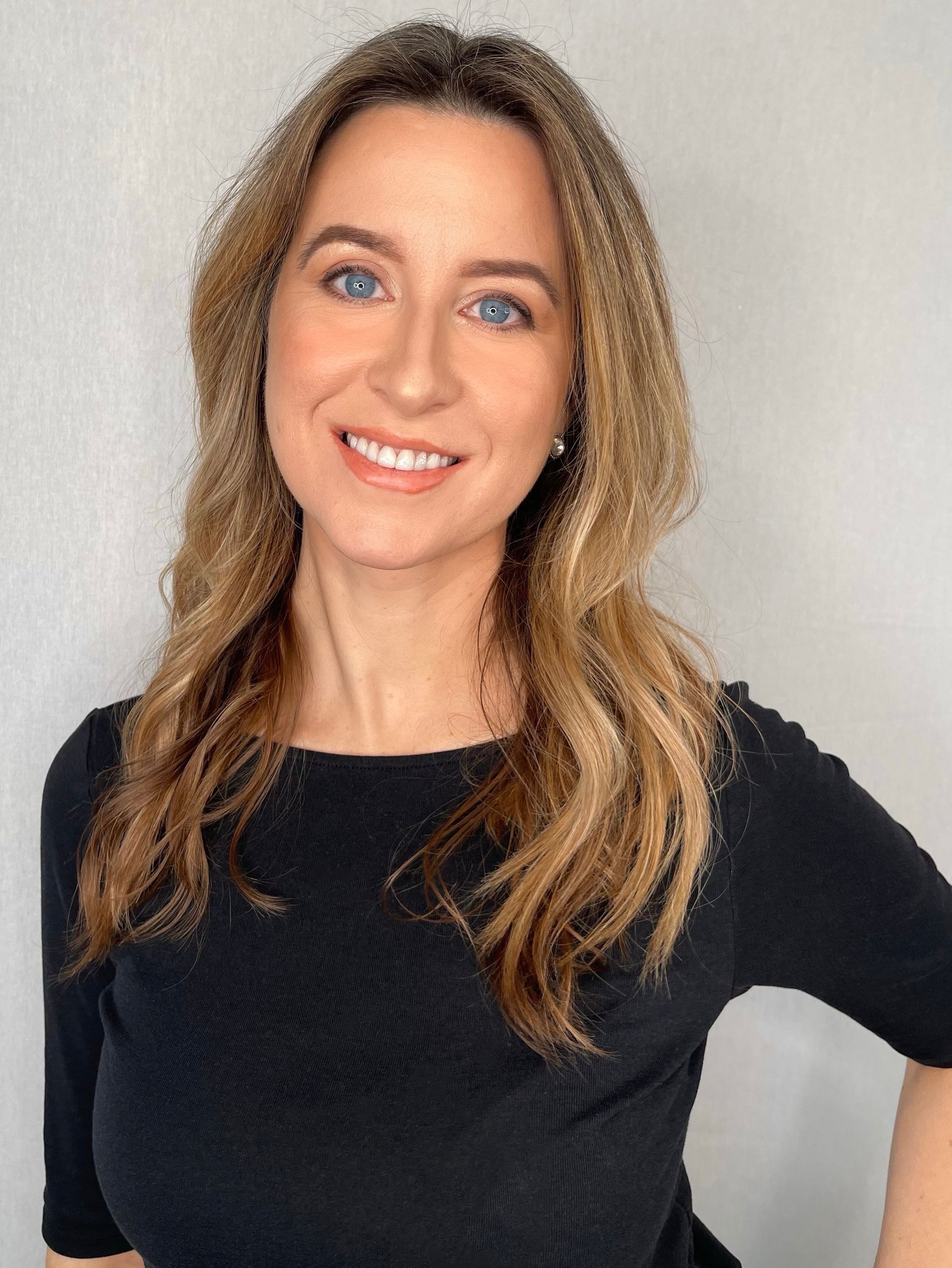 The woman is wearing a black shirt and smiling for the camera.