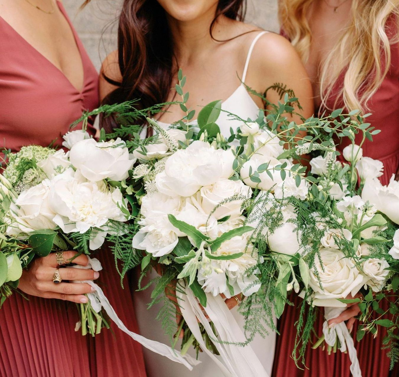 A bride and her bridesmaids are holding bouquets of white flowers.