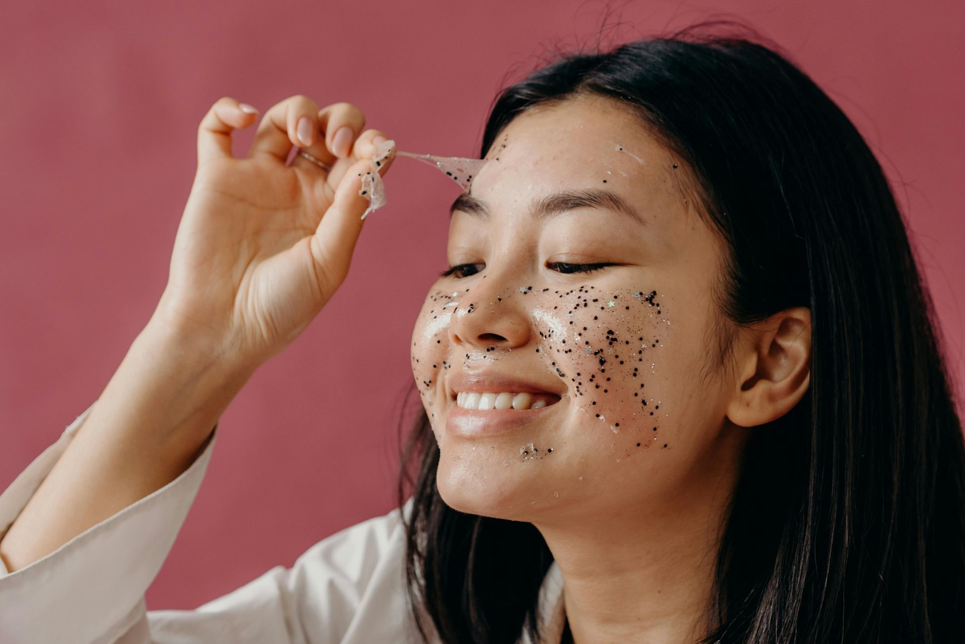 A woman is smiling while peeling a custom chemical facial peel
