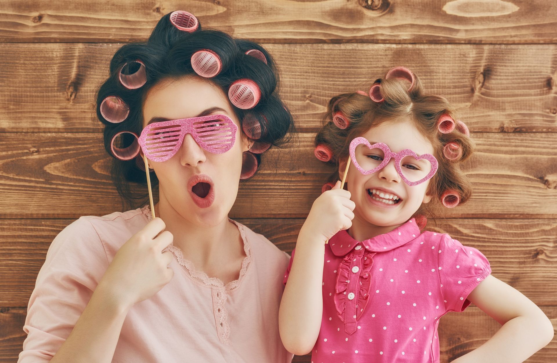 A woman and a little girl with curlers on their hair are making funny faces.