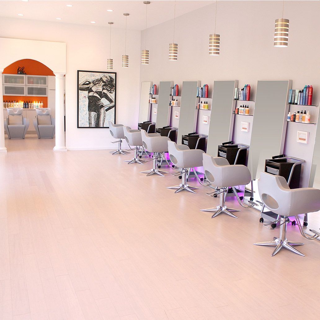 A row of hair salon chairs are lined up in a room
