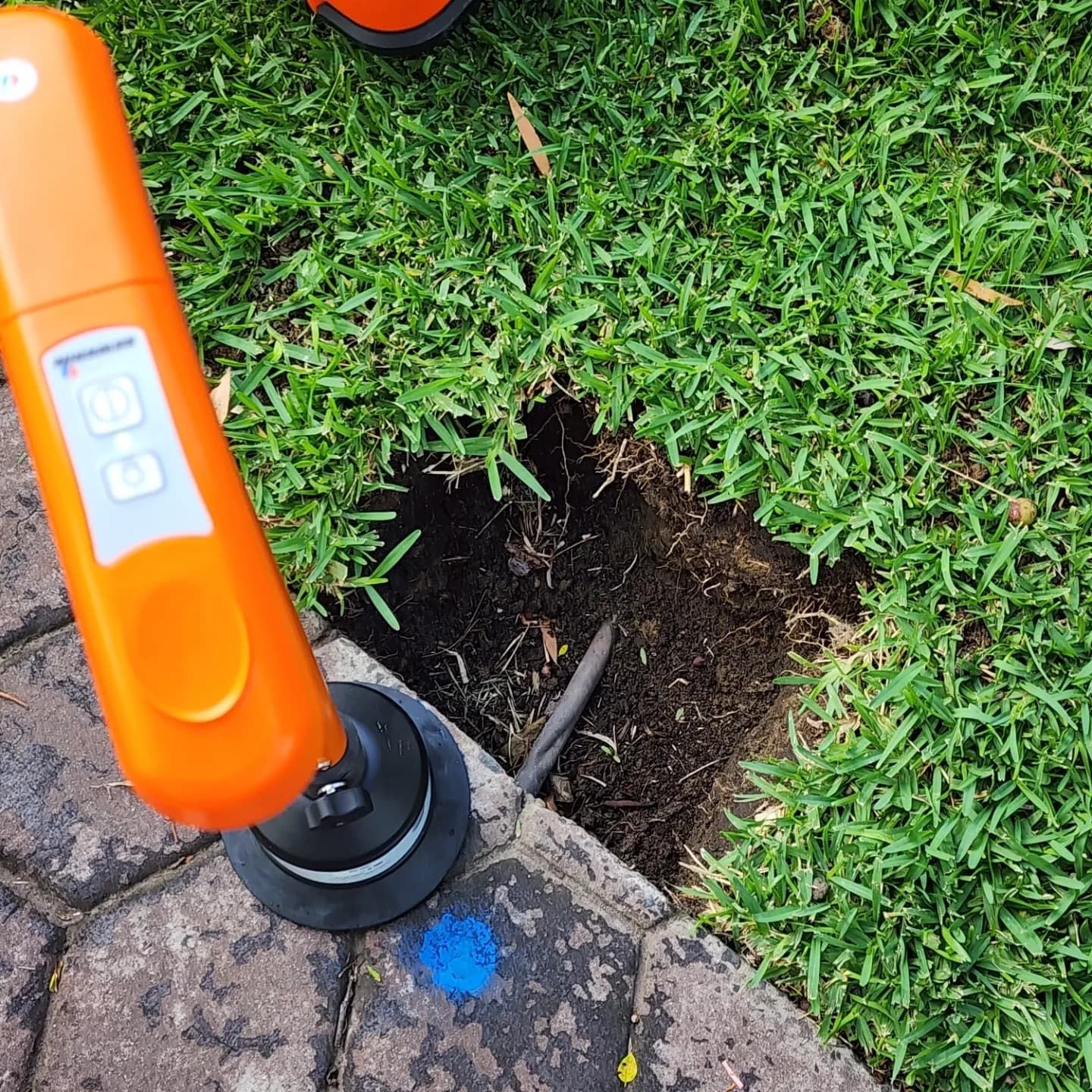 A pot hole has been cut out of grass revealing a pipe — Dowds Pipe and Cable Locating in Farmborough Heights, NSW