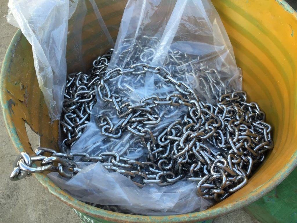 A yellow bucket filled with chains in a plastic bag