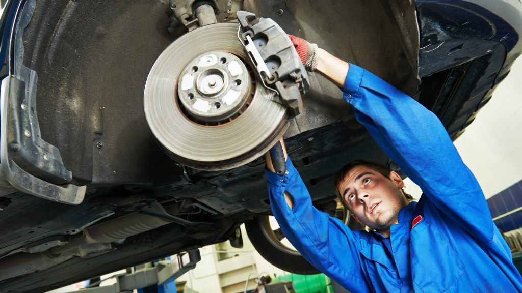 A man is working on a brake disc on a car. | Karta Motorwerks